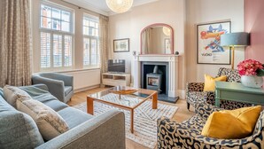 Una sala de estar con chimenea, sofá, sillón y televisor.