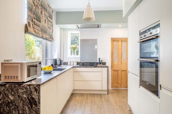 A modern kitchen with a microwave, oven, and a bowl of lemons on the counter.