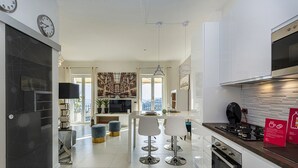 A modern kitchen with a built-in oven, a dining area with bar stools, and a large window offering a view of the city. - Elegant sea View Apartment by Wonderful Italy (Rapallo)