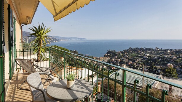 A balcony with a table and chairs, a potted plant, and a view of the sea and town. - Elegant sea View Apartment by Wonderful Italy (Rapallo)