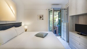 A bedroom with a bed, a TV, a nightstand, and a window with a view of greenery. - Elegant sea View Apartment by Wonderful Italy (Rapallo)