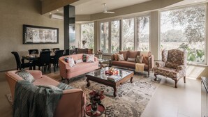 A spacious living room with a large window, a dining area, and a cozy seating arrangement. - Amã Stays & Trails Assa 360, Goa (Anjuna)