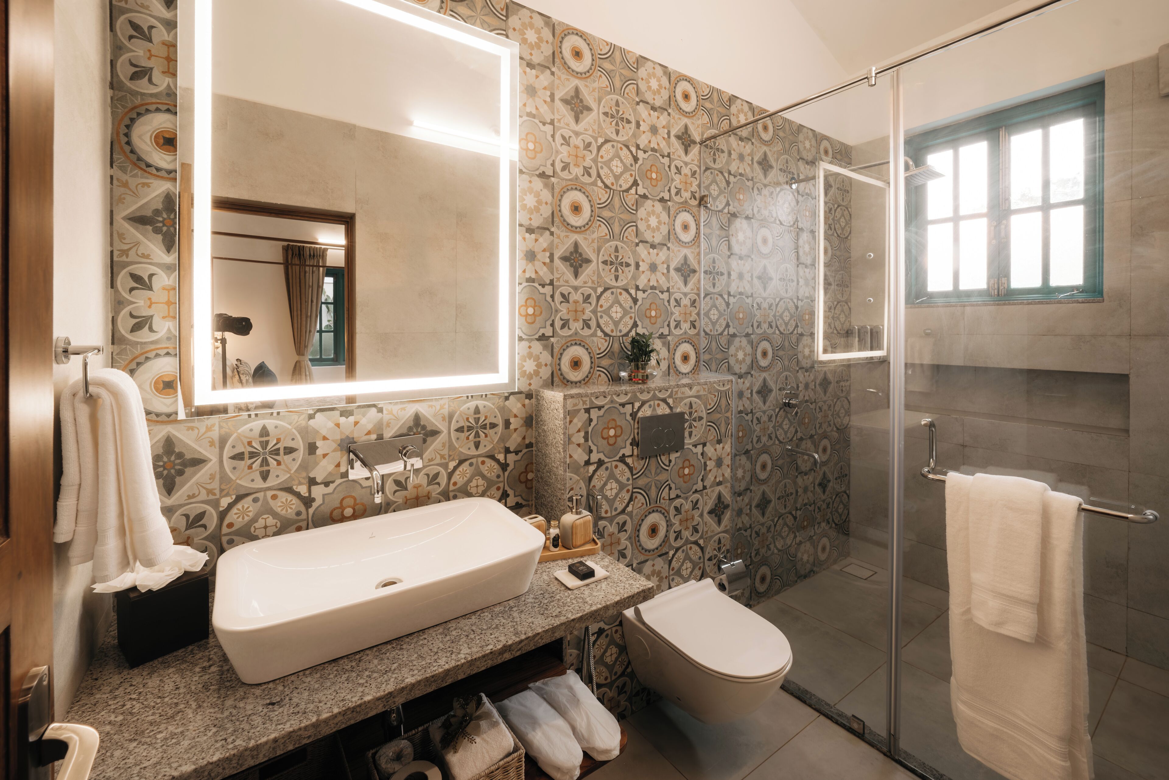 A bathroom with a large mirror, a sink, a toilet, and a shower area.