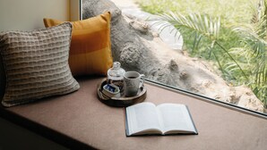 A window seat with a view of a building, a tree, and a small garden. - Amã Stays & Trails Assa 360, Goa (Anjuna)