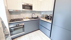A compact kitchen with a microwave, gas stove, oven, and modern appliances.
