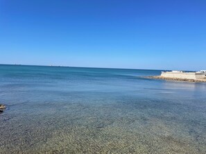 A clear view of a beach with calm waters and a distant ship. - 2-bedroom garden house in Civitavecchia with AC, WiFi. Close to everything !! (Civitavecchia)