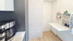 A compact kitchen with a built-in oven, a white tiled backsplash, and a wooden floor.