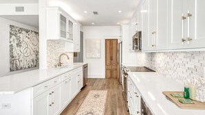 A modern kitchen with white cabinetry, a wooden floor, and a patterned rug.