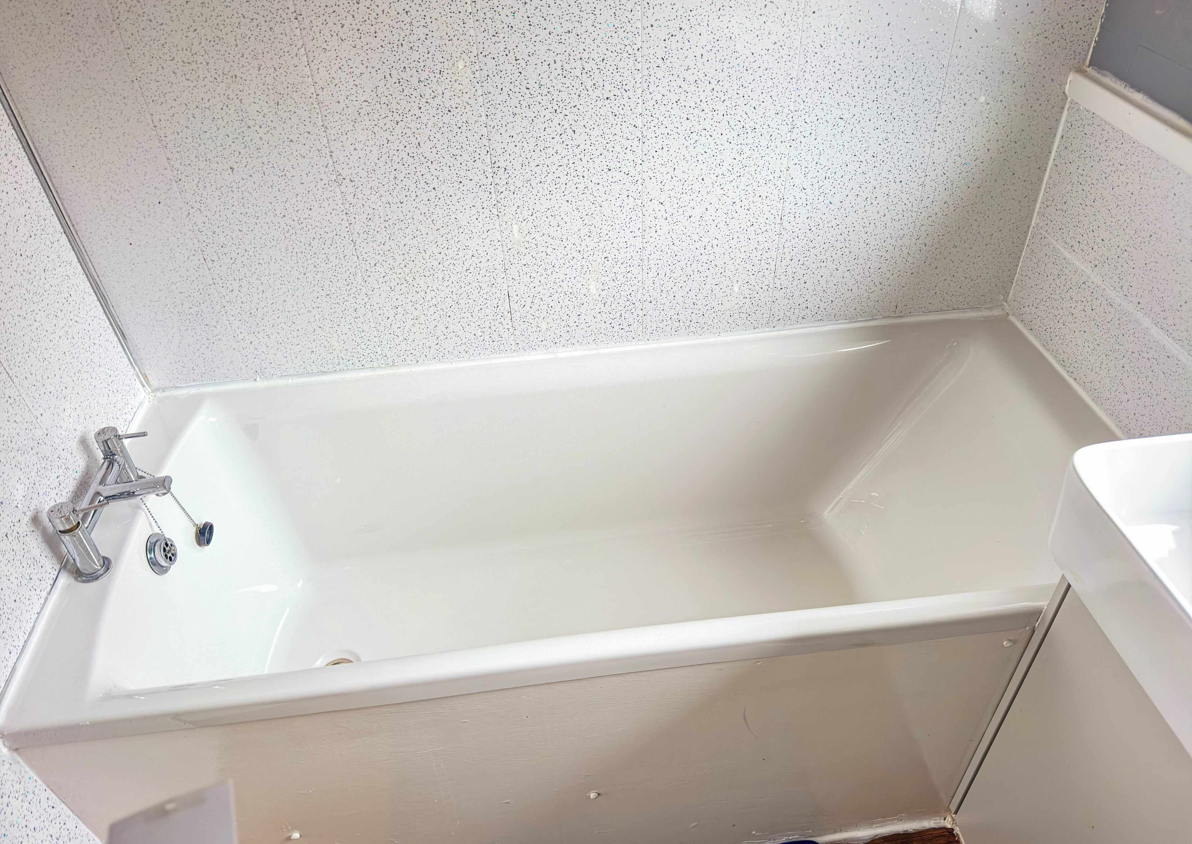 Une salle de bain avec une baignoire blanche, un robinet chromé et un lavabo blanc.