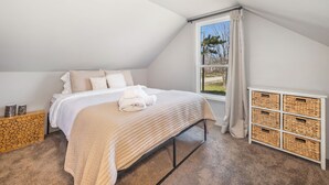Un dormitorio con una cama, una ventana y un mueble de almacenamiento.