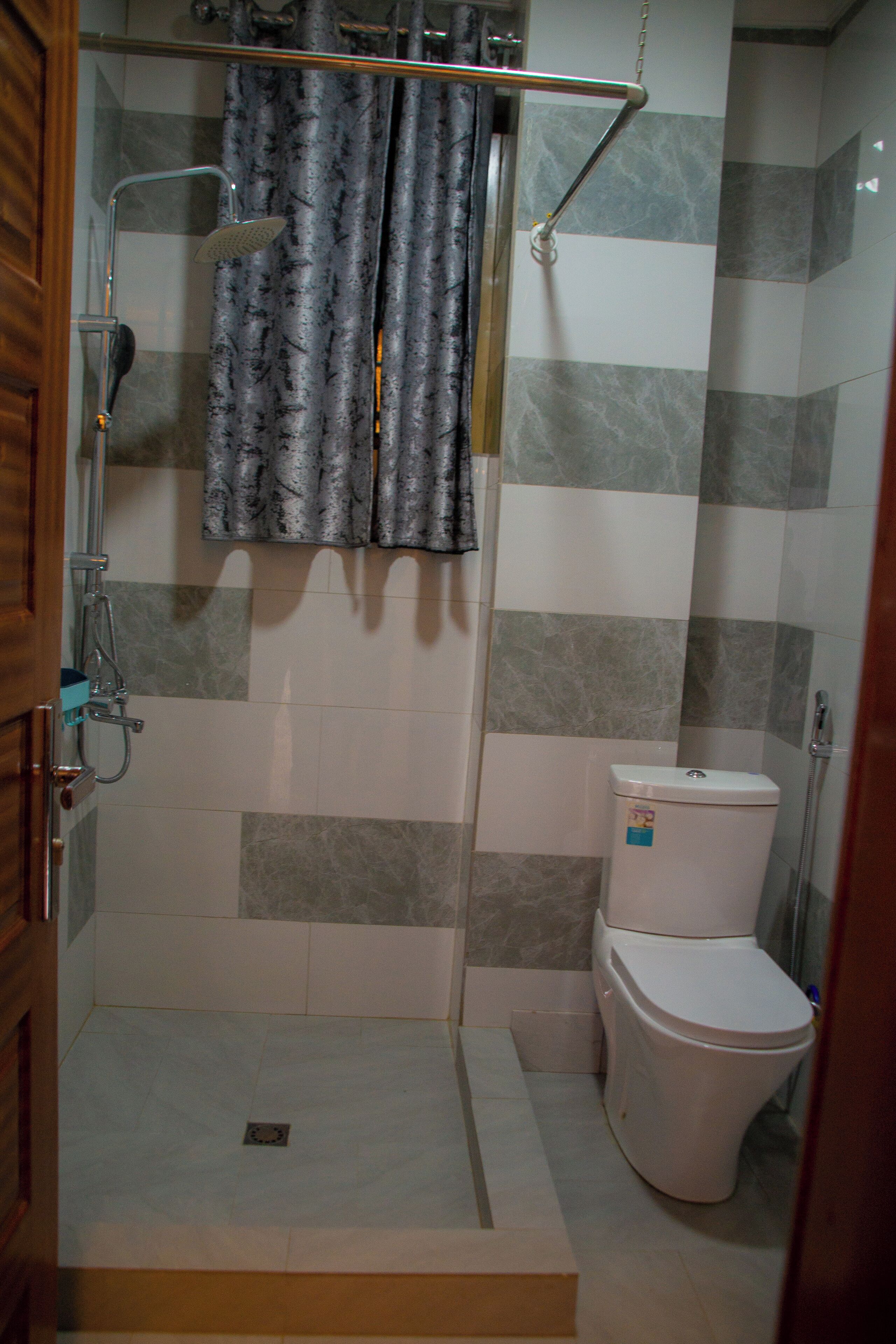A shower area with a glass door, a toilet, and a showerhead.