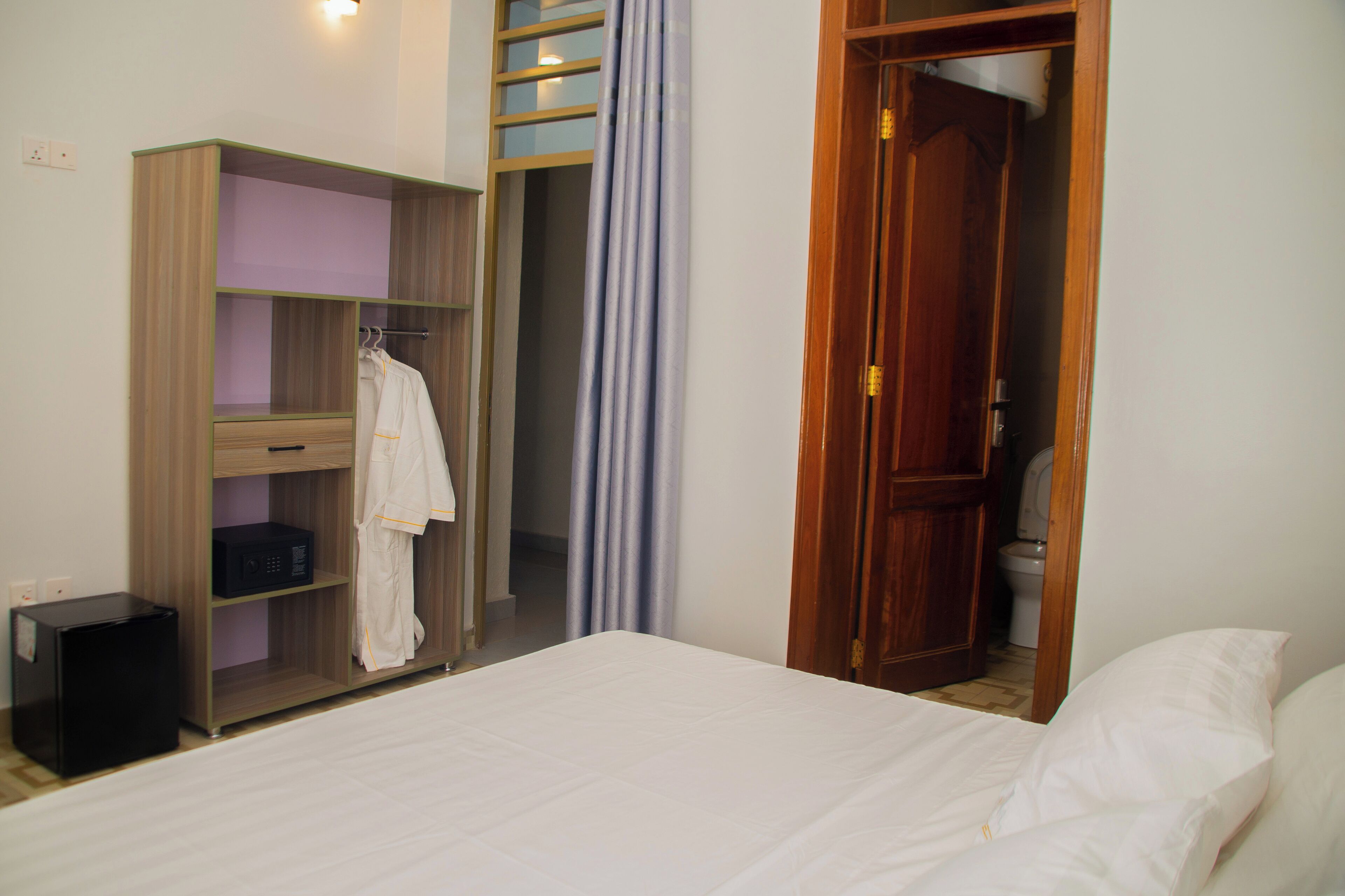 A bedroom with a bed, a wardrobe, and a bathroom.