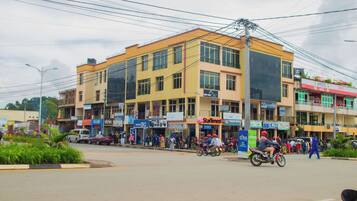 A multi-story building with various shops on the ground floor, including a visible pharmacy and a newsstand.