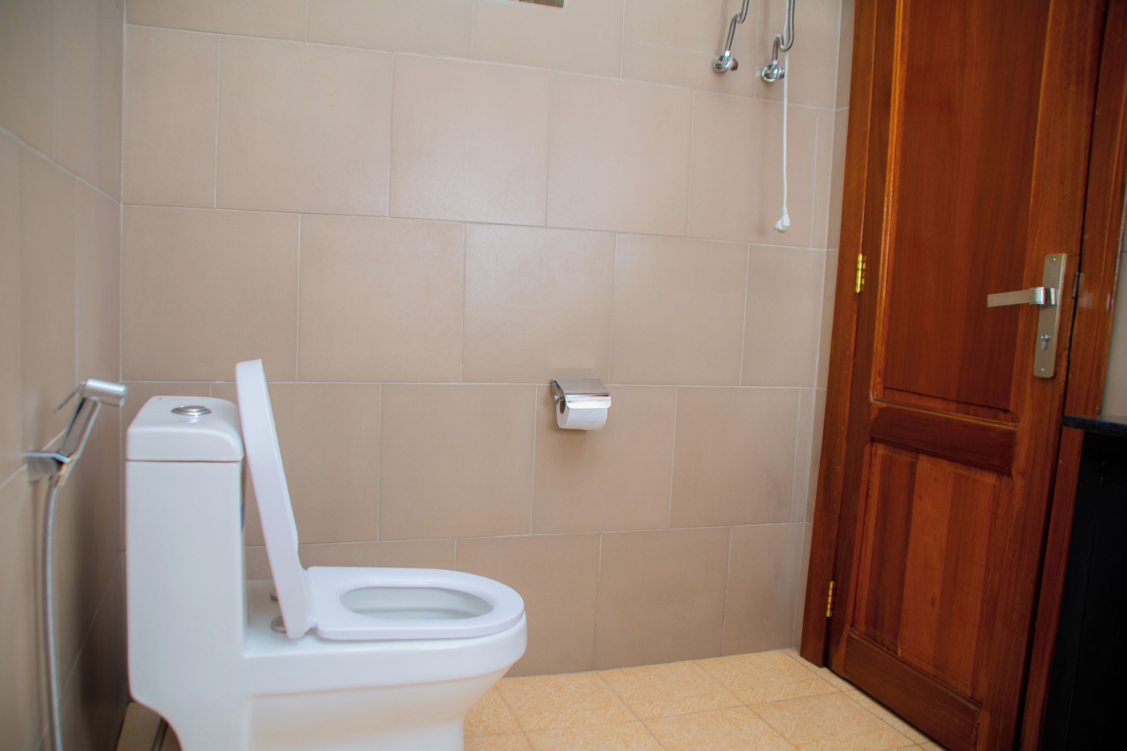 Un baño con inodoro, puerta de madera y zona de ducha.