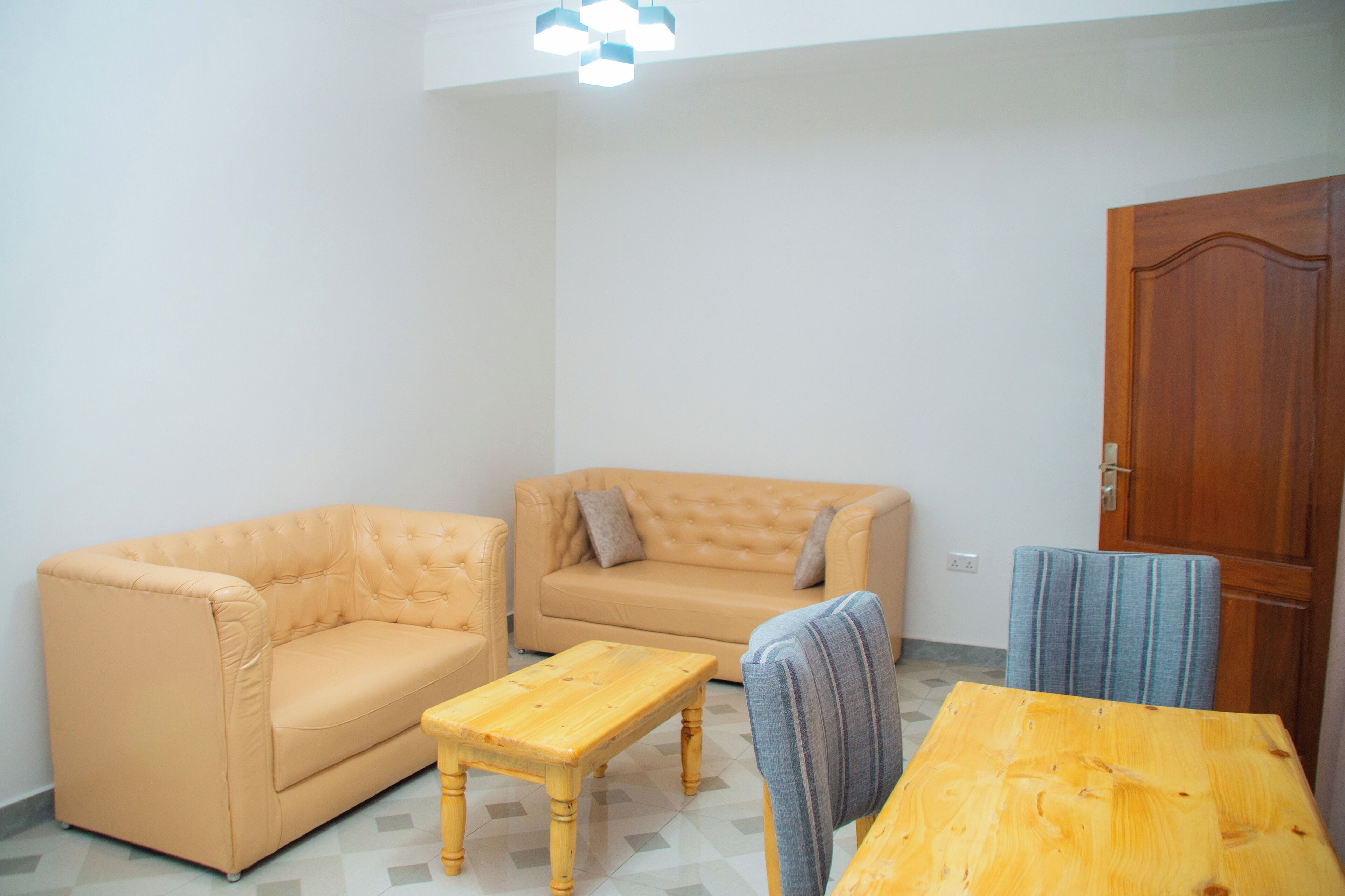 A living room with a beige sofa, a wooden coffee table, and a striped chair.