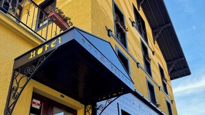 A two-story hotel with a yellow facade, a black awning, and a sign that reads "Hotel". - Hotel La Tour d'Aï (Leysin)