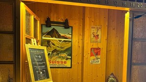A wooden counter with a sign for 'Arrivée Autonome' and 'Suisse' services, a vintage clock, and a framed picture of a mountain landscape. - Hotel La Tour d'Aï (Leysin)