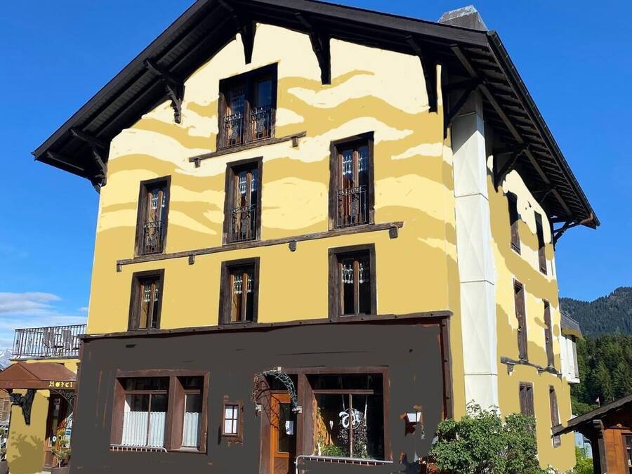 Un immeuble à plusieurs étages, doté d’une façade jaune, de balcons en bois et d’une entrée imposante avec une porte en bois.