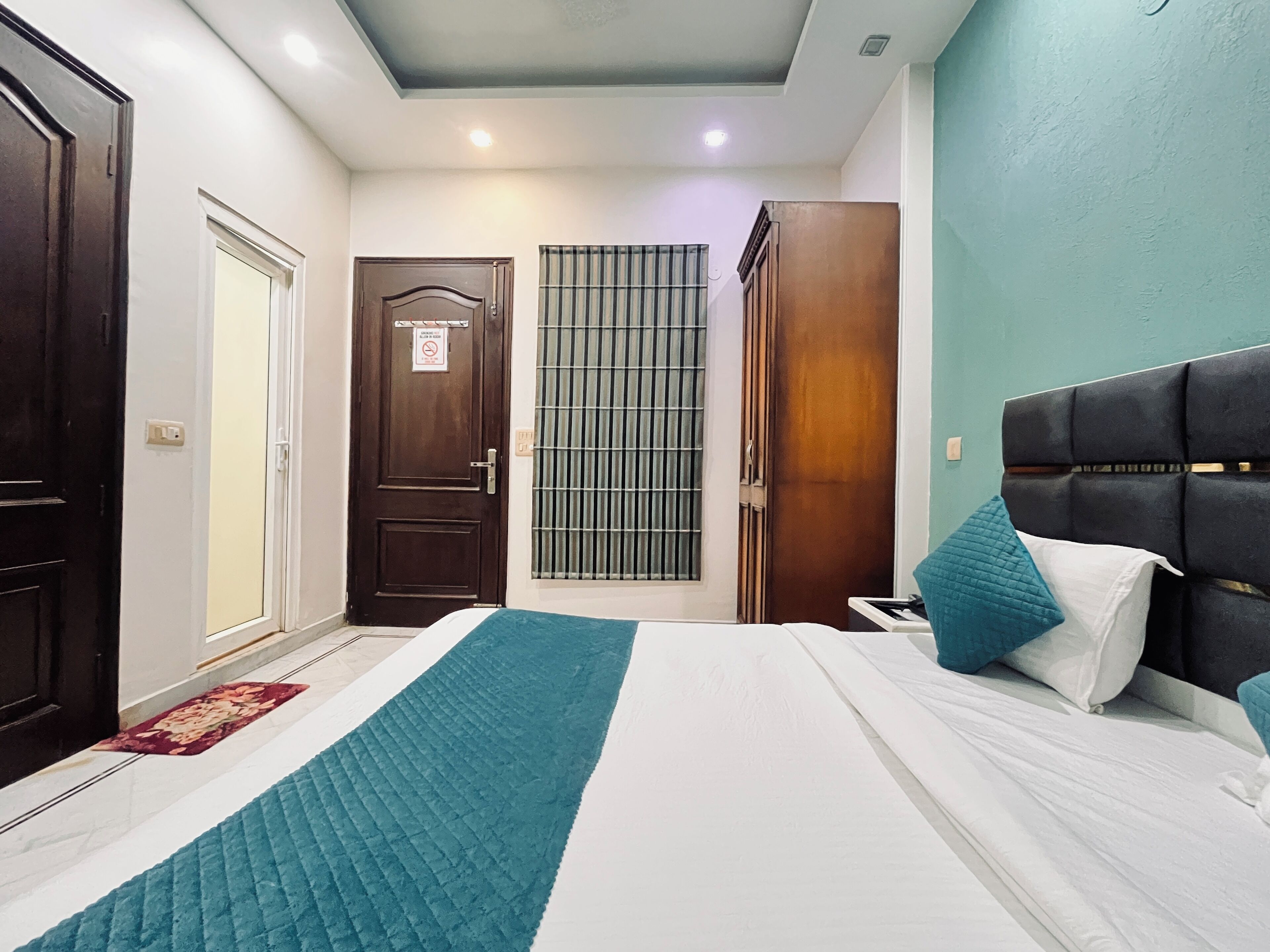 Una habitación de hotel con una cama, una mesita de noche, un armario y una puerta con un cartel.
