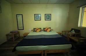 A bedroom with a single bed, two framed pictures on the wall, and a window to the right.