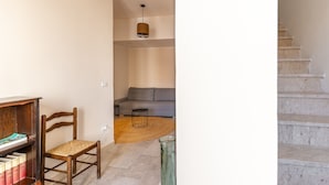 A staircase leading to a living area with a sofa, a wooden chair, a bookshelf, and a hanging light fixture. - Casa Verga con Terrazza by Wonderful Italy (Noto)