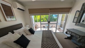 A hotel room with a large bed, a desk, and a view of the outdoors.