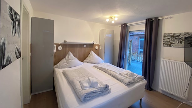 Hotellihuone, jossa on sänky, kattovalaisin, patteri ja näkymä ulos.