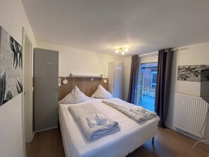 A hotel room with a bed, a ceiling light, a radiator, and a view of the outside. - Ferienwohnungen in Bensersiel (Bensersiel)