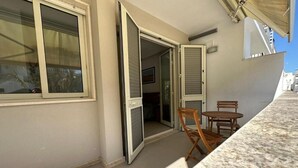 An open sliding door leading to a balcony with a table and chairs. - Room-andromeda Rooms - Fenice (Otranto)