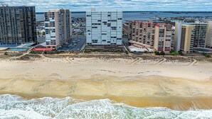 Une zone côtière avec de grands immeubles, une plage de sable et une vue sur l’océan.