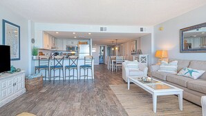 Un vaste espace de vie comprenant une cuisine, un coin repas et un coin salon confortable avec un canapé et une table basse.