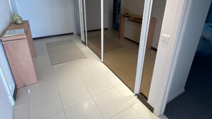 A modern hotel corridor with a tiled floor, a wooden desk, and a wall-mounted vase. - Apartment in Duinbergen Near the Beach (Knokke-Heist)