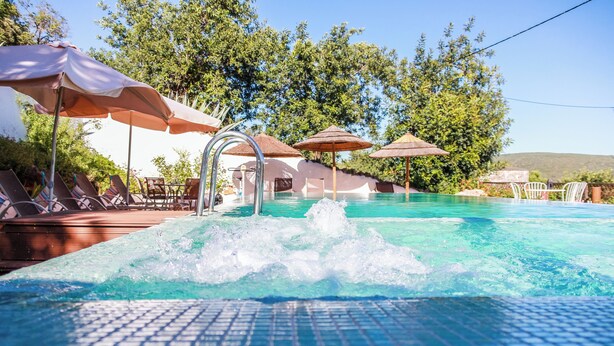 A swimming pool with lounge chairs and umbrellas, surrounded by trees and hills. - Casa da Tita (Loule)