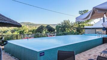 A rectangular swimming pool with a 1.40m depth label, surrounded by a patio area with chairs and a table, and a view of a mountainous landscape.