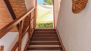 A wooden staircase leading to a room with a kitchen area, including a sink, utensils, and a hanging pot rack. - Casa da Tita (Loule)