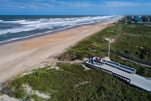 A beach with a boardwalk, a flag, and a structure with people.