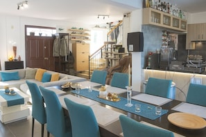 A modern living room with a sofa, chairs, a dining table, and a kitchen area with cabinets and appliances.
