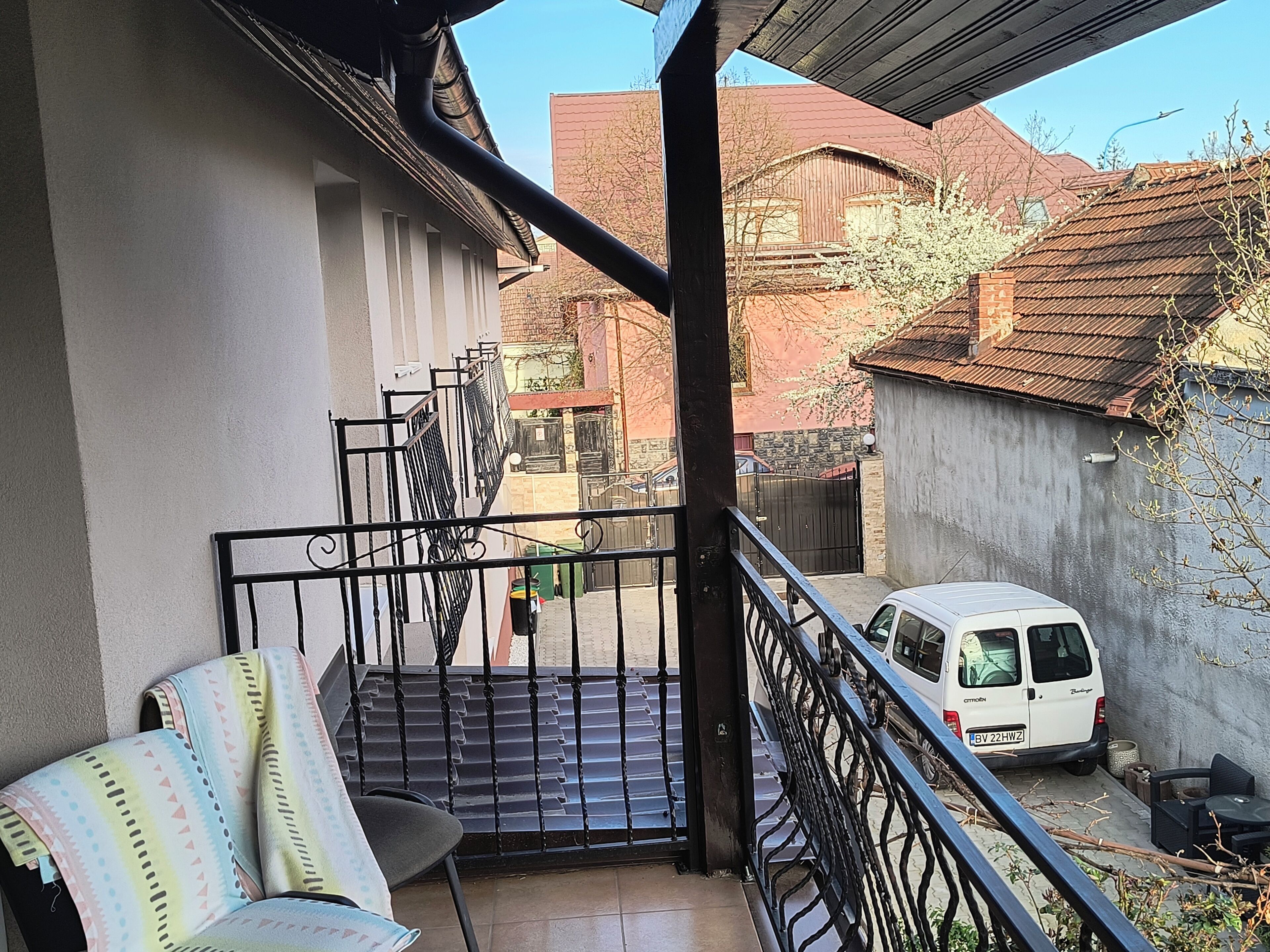 A balcony with a white van parked outside, a staircase, and a chair.