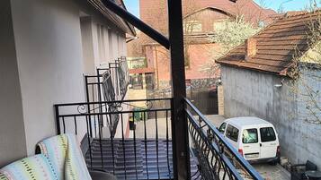 A balcony with a white van parked outside, a staircase, and a chair.