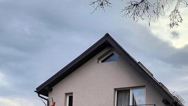 A two-story building with a stone facade, a balcony with a metal railing, and a small window. - Casa Mais (Brasov)
