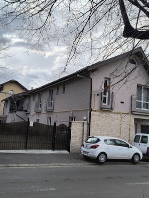 A residential building with a gated entrance, a parked white car, and a visible balcony. - Casa Mais (Brasov)