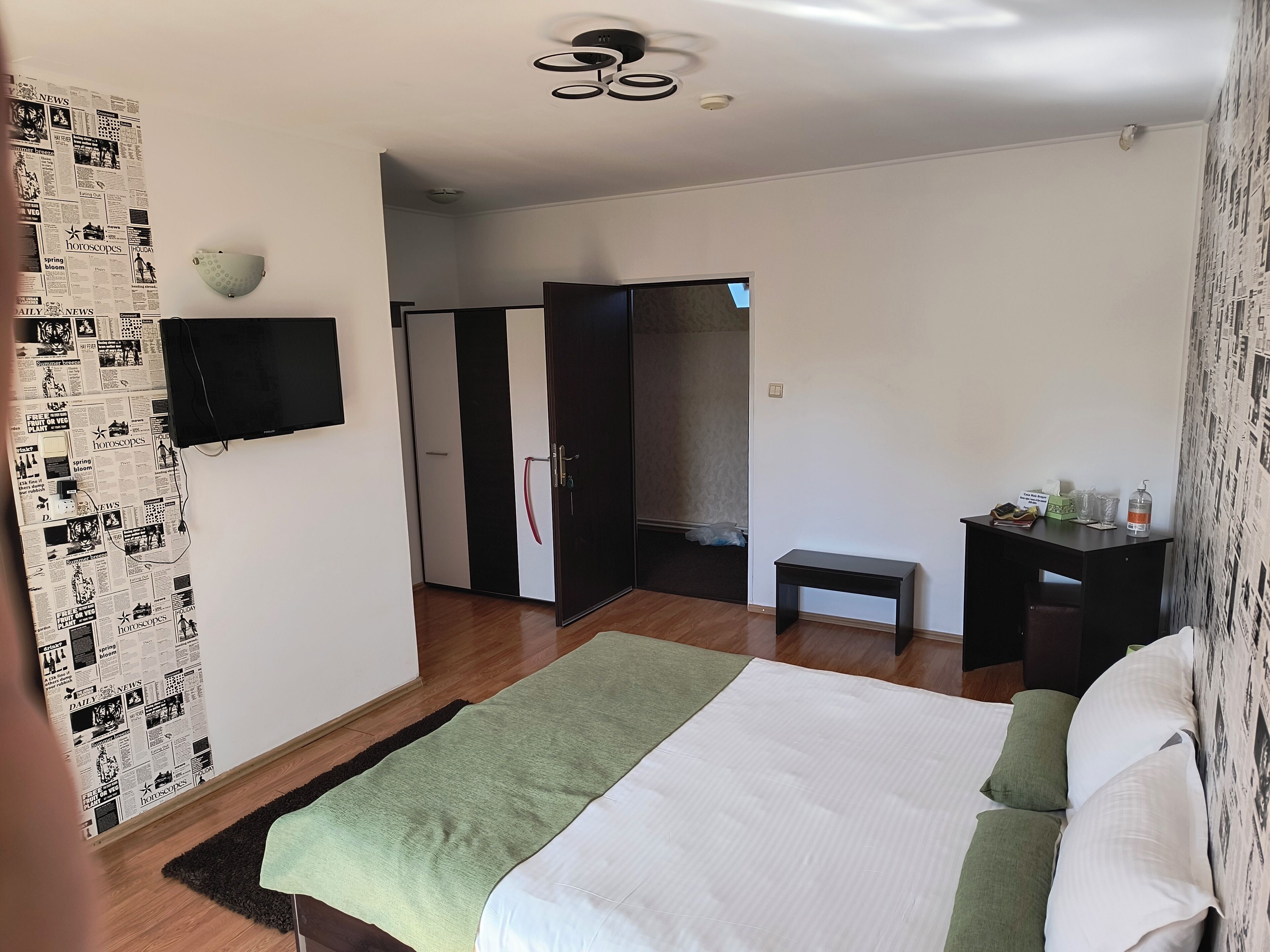 Ein Schlafzimmer mit Bett, Nachttisch, Kleiderschrank und Wandfernseher.