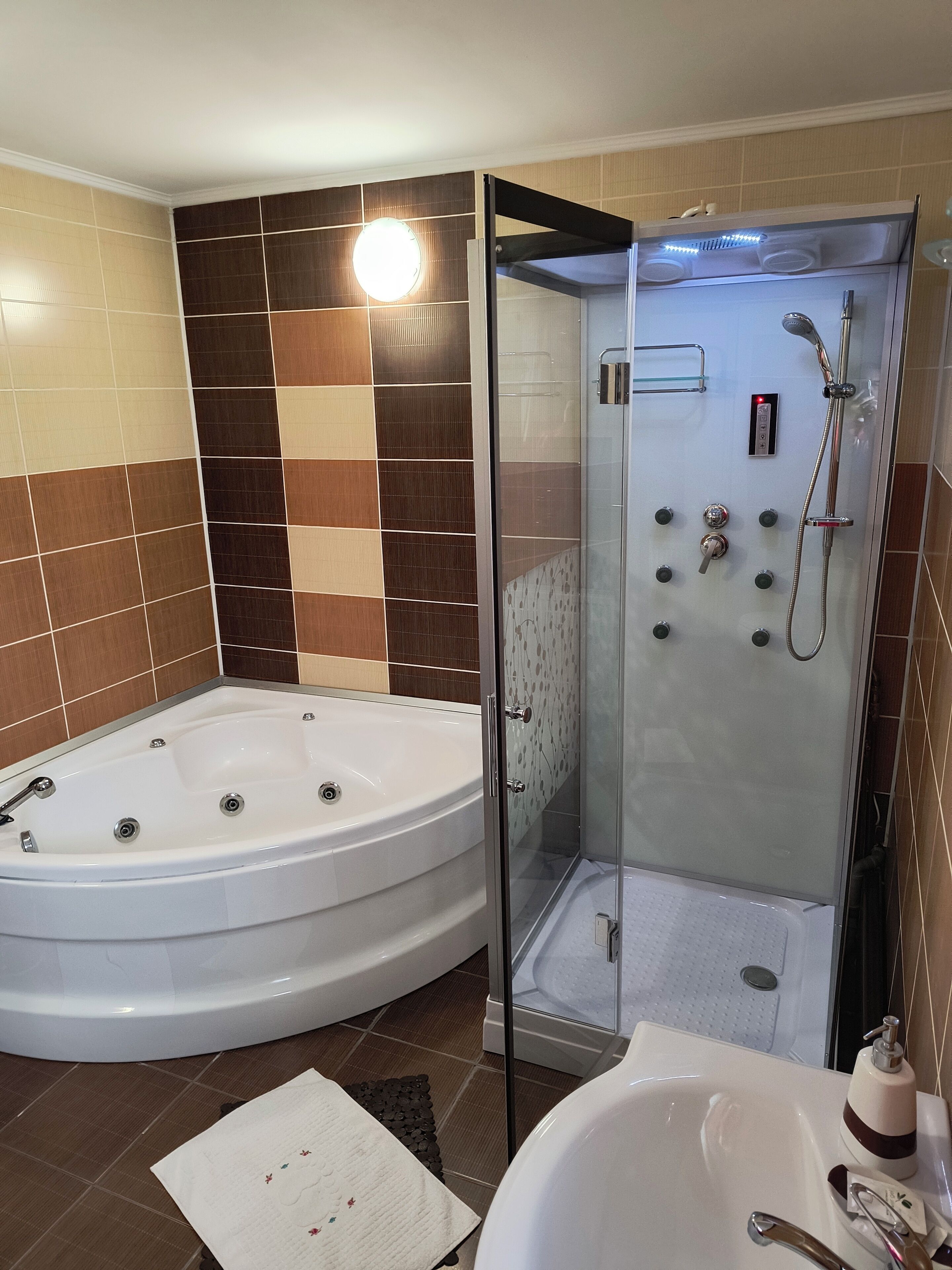 Un baño moderno con una bañera grande, una ducha con mampara de vidrio y un lavamanos separado.