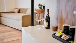 A modern living room with a sofa, a coffee table with a bottle of champagne, two glasses, a candle, and a tray with cards. - florence medali rooms  (Florence)