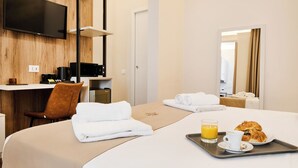 A hotel room with a bed, a desk with a computer, a TV mounted on the wall, and a breakfast tray with croissants and orange juice. - florence medali rooms  (Florence)