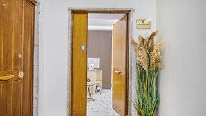 A hallway with a wooden door, a welcome mat, a potted plant, and a sign indicating the location. - florence medali rooms  (Florence)