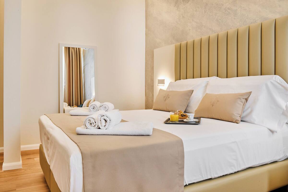 A hotel room with a bed, a tray with breakfast, and a window with curtains.