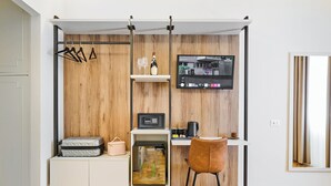 A compact living space with a kitchenette, a mounted TV, a seating area, and a wooden wall panel. - florence medali rooms  (Florence)
