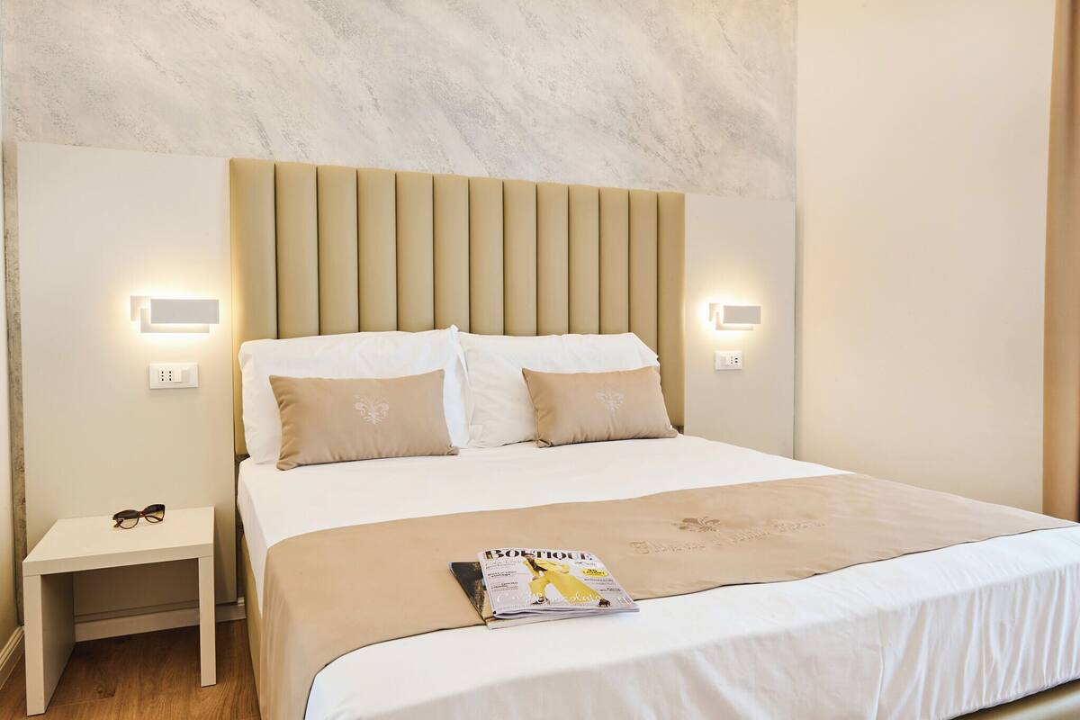 A hotel room with a large bed, a nightstand, and a magazine on the bed.