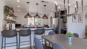 A modern kitchen with a central island, bar stools, and pendant lighting.